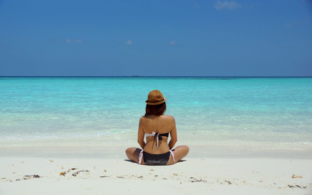 woman wearing black and white brassiere sitting on white sand